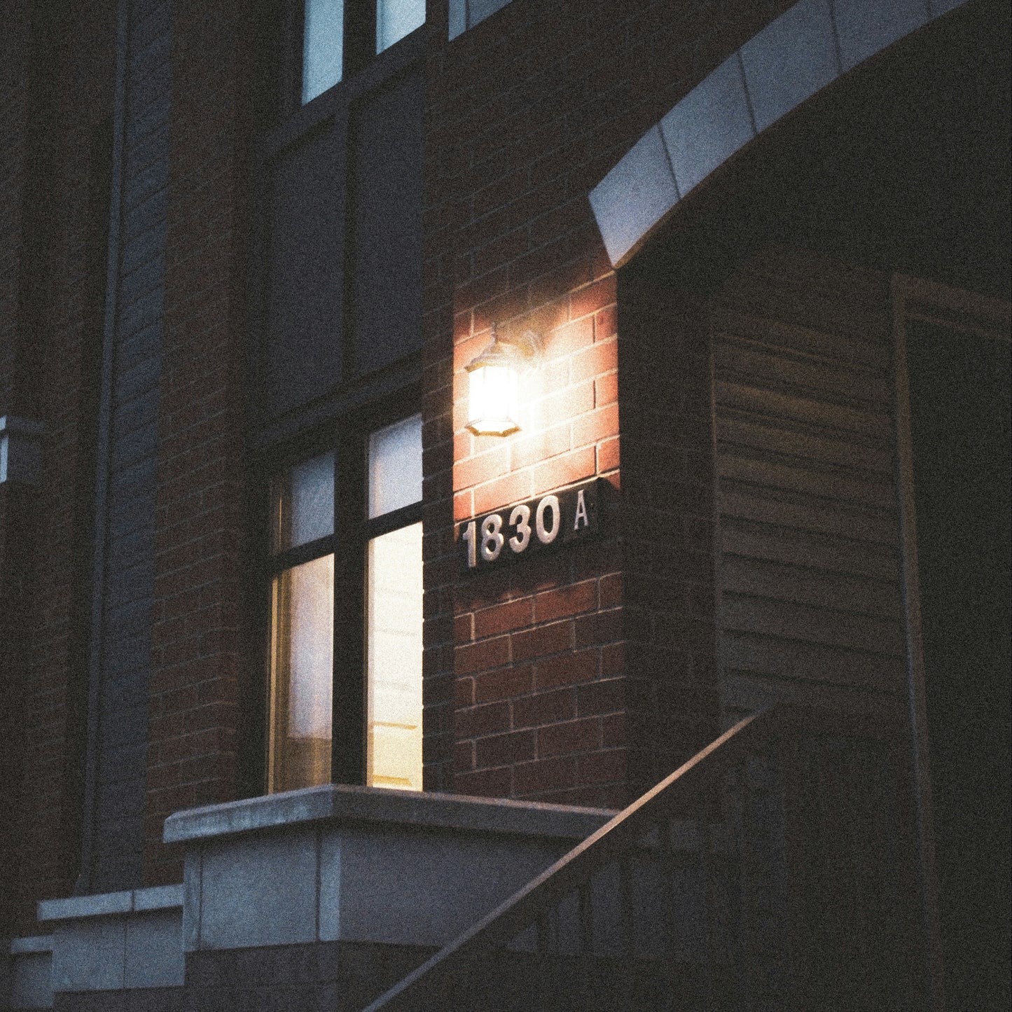 Building entrance with a light fixture and number '1830A' at night.