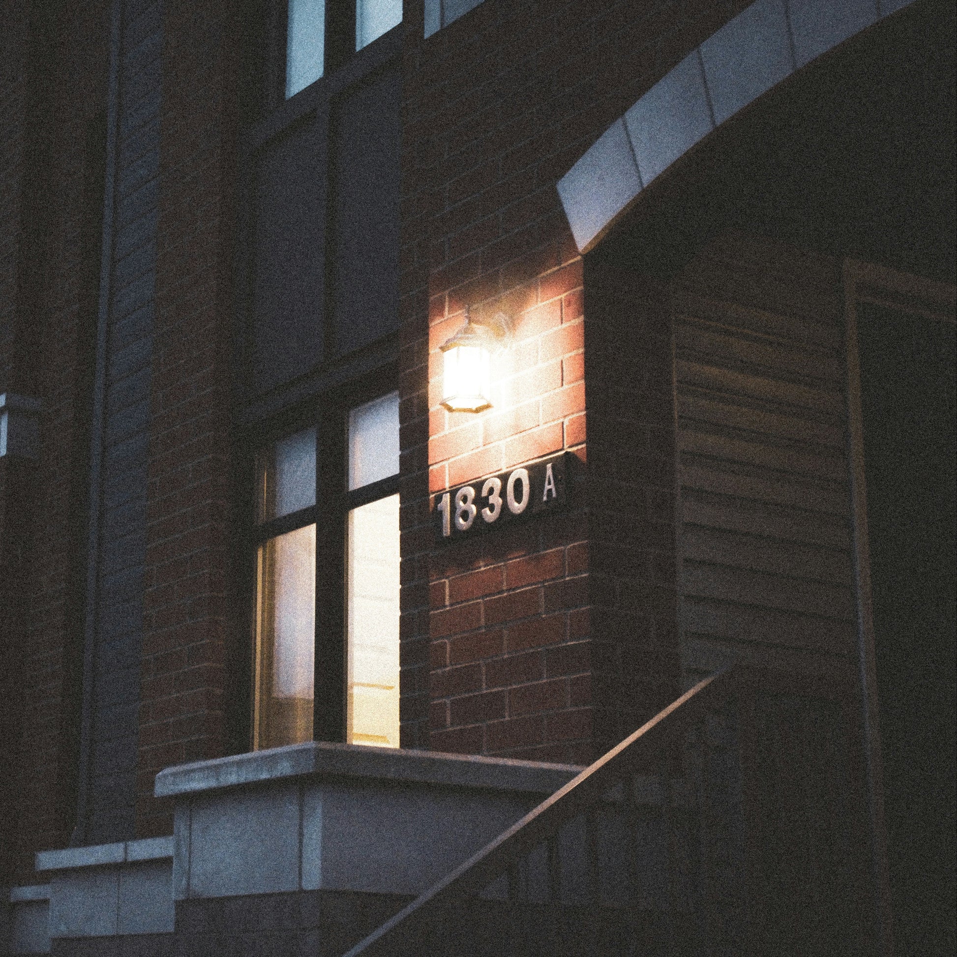 Building entrance with a light fixture and number '1830A' at night.