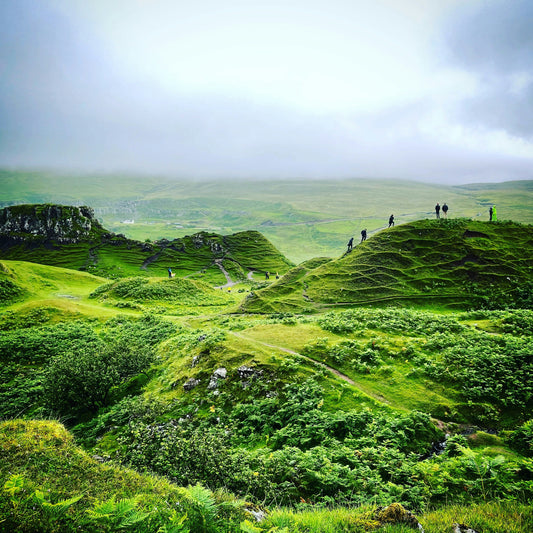 Green landscape with people on a hill under a cloudy sky