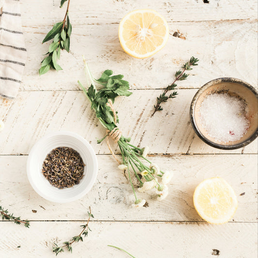 Herbs and spices on a wooden surface with lemons and a towel.